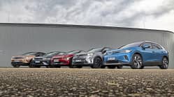 Fünf aktuelle Elektro-SUVs (Hyundai IONIQ 5, VW ID.4 Pro, Opel Grandland, Kia EV6, Renault Scenic E-Tech Electric) nebeneinander vor moderner Industriehalle, fotografiert aus niedriger Perspektive.