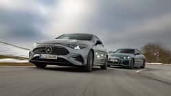 BMW i4 xDrive40 Gran Coupe und Mercedes CLA 350 EQ fahren auf einer Landstraße bei winterlichen Bedingungen.