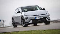 Kia EV4 GTline, Elektroauto, Kia, Stadtfahrzeug, Crossover, 2025, E-Mobilität, Frontansicht, Straßenfahrzeug, Automobil Kia EV4 GTline auf einer Straße, Fahrzeug frontal leicht von unten fotografiert, graues Wetter, urbaner Kontext.