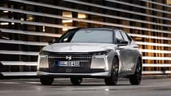 DS N4 Hybrid Pallas, DS N4 HYBRID PALLAS, Hybridfahrzeug, Limousine, Frontalansicht, DS Automobiles, Plug-in-Hybrid, 2024, Premium-Limousine, Automobil DS N4 Hybrid Pallas vor moderner Architektur, frontal aufgenommen.