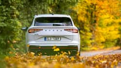 Heckansicht eines weißen Skoda Enyaq RS 79 kWh auf einer herbstlichen Straße, umgeben von buntem Laub.