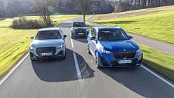 Drei Kompakt-SUVs (Audi SQ2, BMW X1 M35i, Mini JCW Countryman) fahren nebeneinander auf einer Landstraße.