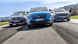 Drei aktuelle Hybrid-SUVs – BMW X1 xDrive 30e, Renault Rafale Hyper Hybrid E-Tech und Cupra Terramar VZ e-Hybrid – fahren nebeneinander auf einer Landstraße. Die Fahrzeuge sind aus der Frontperspektive in Bewegung aufgenommen.