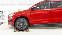 Skoda Karoq, SUV, Fahrzeugtest, Rollenprüfstand, Automobil, Werkstatt, Frontantrieb, Fahrzeugprüfung, 2024, Crossover Rotes Skoda Karoq SUV, Seitenansicht, auf Rollenprüfstand in heller Werkstattumgebung, Fahrer am Steuer.