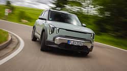 Kia EV2, Elektro-SUV, Kia, Straßenfahrt, Kurvenfahrt, Elektroauto, SUV, Frontansicht, Fahrdynamik, Automobil Kia EV2 auf Landstraße in Kurvenfahrt, Frontalansicht, dynamische Bewegungsunschärfe im Hintergrund.