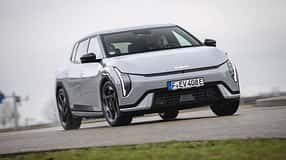 Kia EV4 GTline auf einer Straße, Fahrzeug frontal leicht von unten fotografiert, graues Wetter, urbaner Kontext.