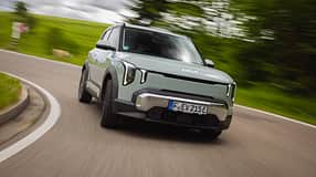 Kia EV2 auf Landstraße in Kurvenfahrt, Frontalansicht, dynamische Bewegungsunschärfe im Hintergrund.