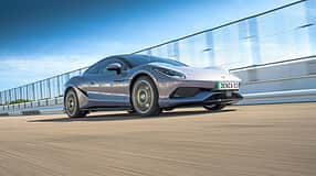 Sportwagen Denza 03 in Fahrt auf einer abgesperrten Teststrecke, aufgenommen bei Tageslicht aus niedriger Perspektive.