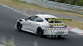 Erlkönig Xiaomi SU7 Ultra Extreme auf dem Nürburgring mit starker schwarz-weiß Tarnung sowie einem gelb abgesetzten großen Heckspoiler.