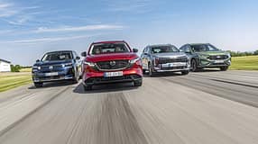 Vier aktuelle SUV-Modelle (Citroën C5 Aircross Hybrid, Mazda CX-5, Kia Sportage, Ford Kuga) fahren nebeneinander auf einer Landstraße. Die Fahrzeuge sind frontal und dynamisch im Verband aufgenommen, alle Modelle sind klar erkennbar.