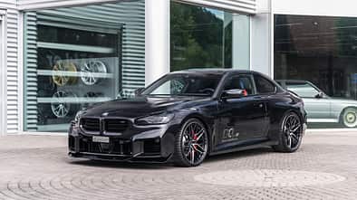 BMW M2 G87 von vorn vor einer Glasfront.