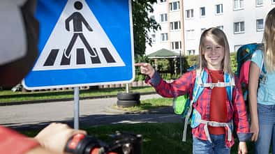 Smiling boy pointing at pedestrian sign