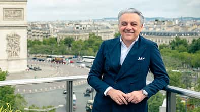 Porträtaufnahme von Luca di Meo, fotografiert bei Publicis im Juli 2025. Die Person steht im blauen Anzug auf einem Balkon mit Stadtblick im Hintergrund.