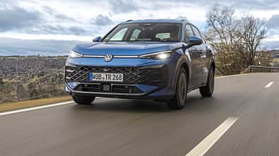 VW T-Roc eTSI auf Landstraße, Frontansicht, fahrend, blauer Kompakt-SUV, Modelljahr 2024.
