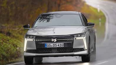 DS N4 Hybrid Pallas auf nasser Landstraße, Frontalansicht, modernes Design, Herbstlandschaft im Hintergrund.