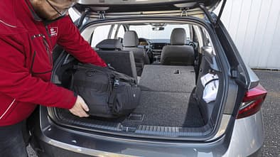 Kofferraumansicht eines Skoda Fabia 1.0 TSI mit umgeklappter Rückbank, Person lädt eine schwarze Tasche ein.