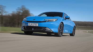 Honda Prelude eHEV i-MMD in Blau fährt auf einer Landstraße, Frontansicht, sportliches Hybrid-Coupé, Modelljahr 2024.
