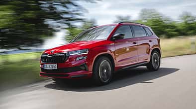 Skoda Karoq 4x4 in Rot fährt auf einer Landstraße, dynamische Außenaufnahme, Fahrzeug in Bewegung.