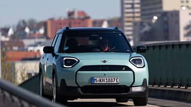 Der Dateiname "Mini Aceman SE 49.2kWh-HDS-06.jpg" und die IPTC-Keywords weisen eindeutig auf das Modell Mini Aceman SE mit 49,2 kWh Batterie hin. Das Bild zeigt einen türkisfarbenen Mini Aceman SE in Frontansicht auf einer Straße im urbanen Umfeld. Die visuelle Analyse bestätigt ein modernes Elektroauto mit typischen Mini-Designmerkmalen.