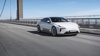 Polestar 5 Dual Motor auf einer Brücke, fahrend von links nach rechts, in Seitenansicht.