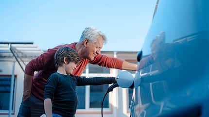 EON Grandfather and grandson charging electric car