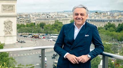 Porträtaufnahme von Luca di Meo, fotografiert bei Publicis im Juli 2025. Die Person steht im blauen Anzug auf einem Balkon mit Stadtblick im Hintergrund.