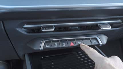 Detailaufnahme der Mittelkonsole eines Audi Q3 SUV TFSI quattro mit Bedienfeld und Finger, der eine Taste betätigt.