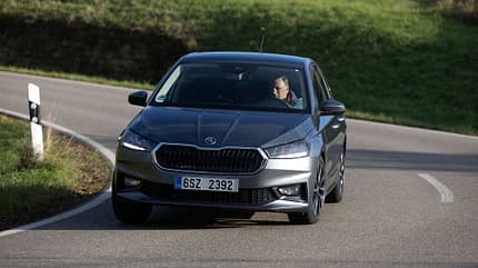 Der Dateiname 'Skoda Fabia 1.0 TSI-HDS-16.jpg' und die IPTC-Keywords nennen das Modell 'Skoda Fabia 1.0 TSI'. Das Bild zeigt einen silbernen Skoda Fabia 1.0 TSI auf einer Landstraße in Kurvenfahrt, fotografiert von vorn. Ein Fahrer ist am Steuer zu erkennen. Die Umgebung ist grün und ländlich.