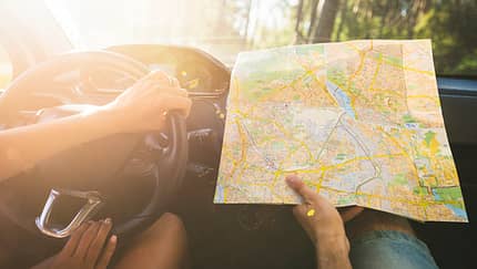 Ein Paar sitzt im Auto und hält eine Landkarte in den Händen.