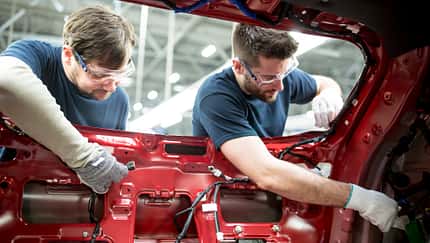 Two colleagues working at bodywork in modern car factory
