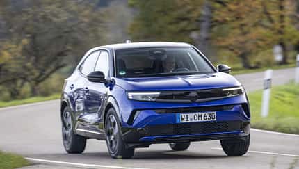 Opel Mokka Hybrid, Hybrid-SUV, Opel, Straße, Kompakt-SUV, Hybridantrieb, Fahrzeug, Automobil, Landstraße, Fahrdynamik Opel Mokka Hybrid fährt auf einer Landstraße durch eine herbstliche Landschaft.