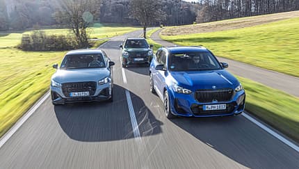 Drei Kompakt-SUVs (Audi SQ2, BMW X1 M35i, Mini JCW Countryman) fahren nebeneinander auf einer Landstraße.