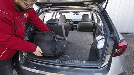 Kofferraumansicht eines Skoda Fabia 1.0 TSI mit umgeklappter Rückbank, Person lädt eine schwarze Tasche ein.