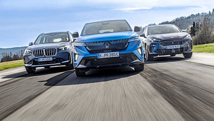 Drei aktuelle Hybrid-SUVs – BMW X1 xDrive 30e, Renault Rafale Hyper Hybrid E-Tech und Cupra Terramar VZ e-Hybrid – fahren nebeneinander auf einer Landstraße. Die Fahrzeuge sind aus der Frontperspektive in Bewegung aufgenommen.