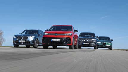 Vier Mittelklasse-SUVs im direkten Vergleich: Mercedes GLC 220d 4Matic, BMW X3 xDrive 20d, Alfa Romeo Stelvio 2.0 Diesel und VW Tiguan 2.0 TDI fahren nebeneinander auf einer Straße.