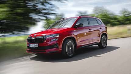 Skoda Karoq 4x4, SUV, Allradantrieb, Kompakt-SUV, Skoda, Fahrzeug, Straßenfahrt, Automobil, Rot, 2024 Skoda Karoq 4x4 in Rot fährt auf einer Landstraße, dynamische Außenaufnahme, Fahrzeug in Bewegung.