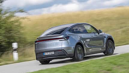 Tesla Model Y AWD, Elektro-SUV, Allradantrieb, Straße, Heckansicht, Tesla, E-Mobilität, SUV, 2025, Automobil Tesla Model Y AWD auf Landstraße, Heckansicht, silberfarbenes Elektro-SUV, ländliche Umgebung.