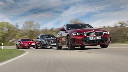Drei Limousinen-Modelle Alfa Romeo Giulia 2.2, BMW 320d und Mercedes C 220d fahren auf einer Landstraße.