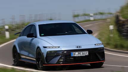 Hyundai Ioniq 6N AWD auf Landstraße in Kurvenfahrt, Frontansicht, sportliches Elektroauto.