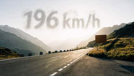 07/2026, Raser Sustenpassstraße Der Sustenpass in der Schweiz im Sonnenuntergang, es spiegelt sich das Licht in der Straße auf dem kein Auto fährt, im Himmel darüber erscheint als Wolke "196 km/h"