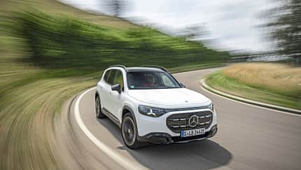 Mercedes GLB 250+, Mercedes-Benz, SUV, Elektro-SUV, Straßenfahrt, 2024, Fahrdynamik, Kurvenfahrt, Automobil, Crossover Mercedes GLB 250+ fährt auf einer kurvigen Landstraße. Das weiße SUV ist in Bewegung, die Umgebung ist verwischt.