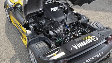 Detailaufnahme des Motorraums eines Ruf 8Zylinder Prototypen mit geöffnetem Heckdeckel. Der V8-Motor und die Fahrwerksstruktur sind deutlich sichtbar.