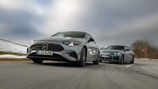 BMW i4 xDrive40 Gran Coupe und Mercedes CLA 350 EQ fahren auf einer Landstraße bei winterlichen Bedingungen.