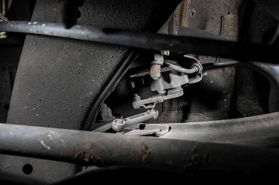 Diese Kinematik dient dem Höhenstandsgeber der Hinterachse. Er versorgt sowohl die Luftfederung mit dem nötigen Höhenstand, wie auch die meist adaptiven Bi-Xenon-, bzw. LED-Scheinwerfer. Ab und an fällt der Sensor aus. Ein Ersatzteil ist meistens zweistellig und nur etwas fummelig zu montieren, da er recht weit innen beim Differenzial sitzt.