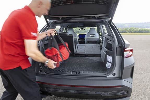 Ein Mann lädt eine Tasche in den Kofferraum eines Autos. Die Rücksitze sind teilweise umgeklappt, um mehr Stauraum zu schaffen.