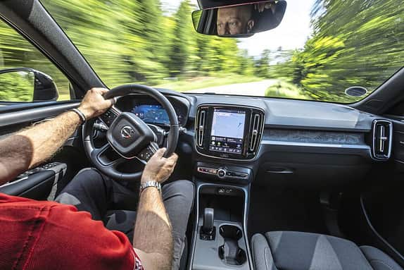 Innenaufnahme eines fahrenden Autos, Blick auf das Armaturenbrett, Lenkrad und Fahrer.