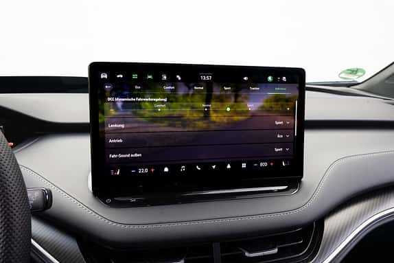 Das Bild zeigt das zentrale Infotainment-Display eines Skoda Enyaq RS 79 kWh mit Fahrwerk- und Fahrmodusanzeige im Innenraum.