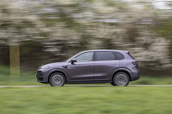 Leapmotor B10 ProMax SUV fährt auf einer Landstraße, Seitenansicht, in Bewegung, Frühlingslandschaft im Hintergrund.