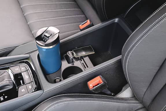 Detailaufnahme der Mittelkonsole eines Skoda Karoq 4x4 mit Getränkehalter, Autoschlüssel und Thermobecher.