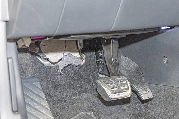 Detailaufnahme des Fußraums und der Pedalerie eines Skoda Karoq, Modelljahr 2018, mit sichtbarer Teppich- und Verkleidungsschädigung.